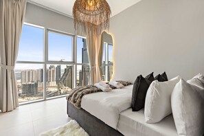 Ein modernes Schlafzimmer mit einem großen Bett, Blick auf die Stadt und einer außergewöhnlichen Hängeleuchte.