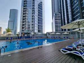 Ein Poolbereich auf dem Dach mit freiem Blick auf hohe Gebäude im Hintergrund.