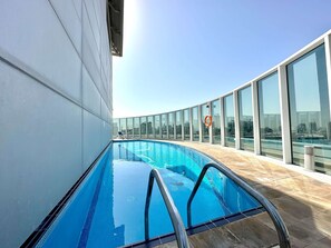 A rooftop swimming pool with clear blue water, surrounded by glass railings and a city view. - Silkhaus Chic Studio Barsha Heights Madison (Dubai)