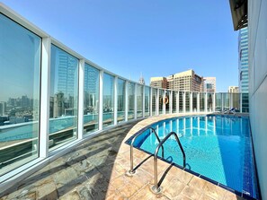 A rooftop pool with glass railings, a clear view of the city skyline, and a tiled floor. - Silkhaus Chic Studio Barsha Heights Madison (Dubai)