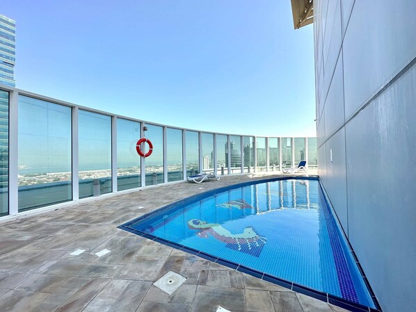 A rooftop pool with clear views of the cityscape, a lifebuoy, and lounge chairs. - Silkhaus Chic Studio Barsha Heights Madison (Dubai)