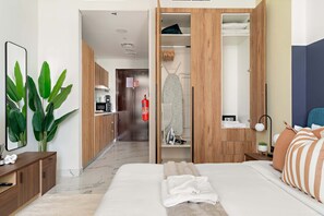 A hotel room with a bed, a wooden wardrobe, a small desk, a mirror, and a potted plant. - Silkhaus New Tower Near Al Reem Adgm (Abu Dhabi)