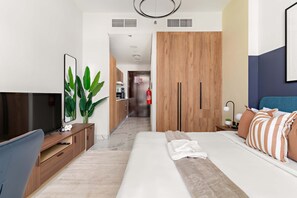 A modern hotel room with a bed, bedside table, TV, and a view of the hallway. - Silkhaus New Tower Near Al Reem Adgm (Abu Dhabi)