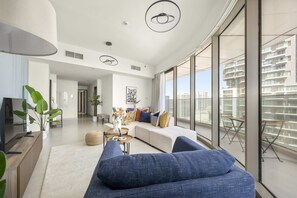 Un salon moderne avec un grand canapé, un téléviseur et un coin repas comprenant une table et des chaises.