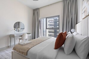 Ein modernes Schlafzimmer mit einem großen Bett, einem Schreibtisch und einem Fenster mit Vorhängen.