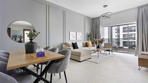 Una sala de estar moderna con un sofá, sillas, una mesa de comedor y un ventanal grande.