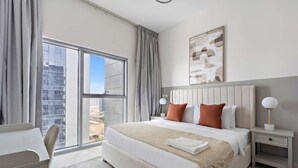 Una habitación de hotel moderna con una cama grande, un escritorio y vistas a la ciudad.