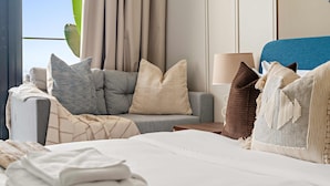 Une chambre d’hôtel avec un lit, un canapé gris et une fenêtre avec des rideaux.