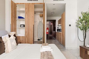 A hotel room with a bed, a wooden wardrobe, a bathroom, and a kitchenette. - Silkhaus Chic Studio Shared Pool and Gym (Abu Dhabi)