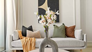 Un salon avec un canapé, un vase de fleurs et un tableau accroché au mur.