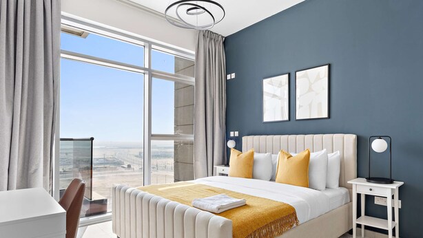 Une chambre d’hôtel moderne dotée d’un grand lit, d’un bureau et offrant une vue sur le paysage urbain.