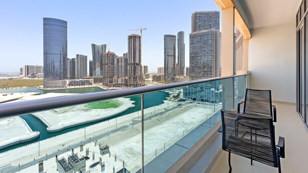 A balcony with a view of a cityscape, including high-rise buildings and a marina. - Silkhaus Julphar Tower By Al Fay Park Al Reem (Abu Dhabi)