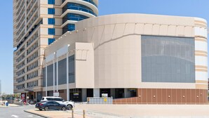 A tall, modern hotel with a curved facade, large windows, and a flat roof. - Silkhaus Julphar Tower By Al Fay Park Al Reem (Abu Dhabi)