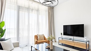 A modern living room with a sofa, a coffee table, a TV, and a plant. - Silkhaus Julphar Tower By Al Fay Park Al Reem (Abu Dhabi)