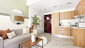 Una sala de estar moderna con un sofá gris, una mesa de centro de madera y un espejo redondo.