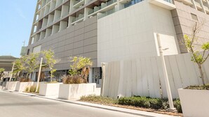 Un edificio alto y moderno con varios balcones, fachada plana y cielo despejado.