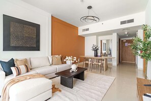 A modern living room with a sofa, coffee table, and a dining area in the background. - Silkhaus Serene 1bdr Stay Near Reem Mall (Abu Dhabi)