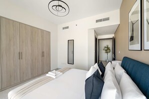 Ein modernes Hotelzimmer mit einem großen Bett, einem Kleiderschrank, einem Spiegel und Blick auf den Flur.