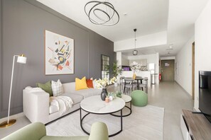 Ein modernes Wohnzimmer mit einer Couch, einem Couchtisch und einem Essbereich im Hintergrund.