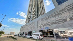 A modern building with a parking entrance and a tall residential tower. - Silkhaus Signature 1bdr Najmat Al Reem Island (Abu Dhabi)