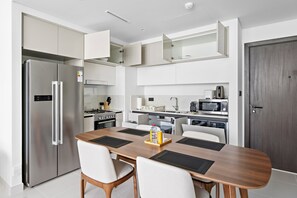 A modern kitchen with a stainless steel refrigerator, a dining table with chairs, and a microwave. - Silkhaus Elite 2bdr Marina Vista Sea View (Dubai)