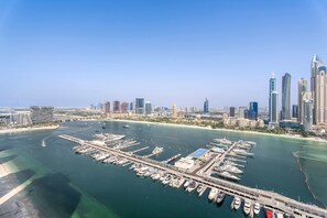 A marina with numerous boats docked, a bridge connecting to the city, and a skyline of modern buildings. - Silkhaus Elite 2bdr Marina Vista Sea View (Dubai)