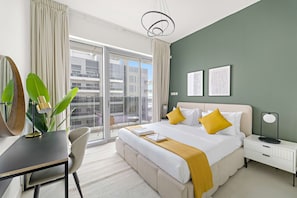 A modern hotel room with a large bed, a desk, a chair, and a view of the city through large windows. - Silkhaus Premium 2bdr Reem Park Najmat (Abu Dhabi)