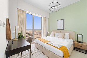 Habitació d'hotel amb un llit gran, una taula de treball, una cadira, una tauleta de nit i vista al desert per la finestra.