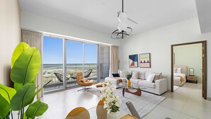 A modern living room with a large sliding glass door leading to a balcony with a city view. - Silkhaus Comfy 1bdr Najmat Tower in Reem Island (Abu Dhabi)
