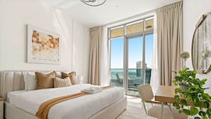 Une chambre d’hôtel moderne dotée d’un grand lit, d’une table à manger, d’une chaise et offrant une vue sur la ville.