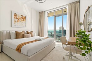 Een moderne hotelkamer met een groot bed, een eettafel, een stoel en uitzicht op de stad.
