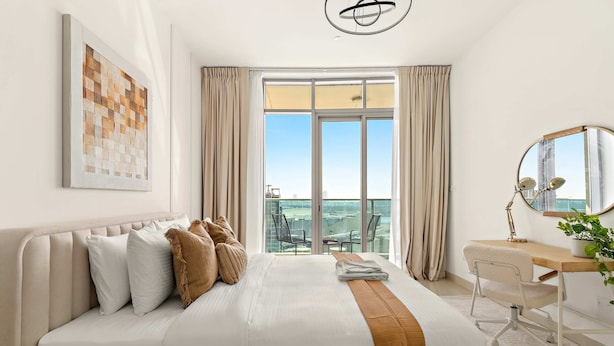 Une chambre d’hôtel moderne dotée d’un grand lit, d’un bureau, d’une chaise, d’une grande fenêtre offrant une vue et d’un luminaire au plafond.