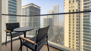 A balcony with two chairs and a small table, overlooking a cityscape with high-rise buildings. - Silkhaus 1bdr Marina Vista Private Beach (Dubai)
