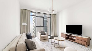 A modern living room with a sofa, armchair, TV, and a small coffee table. - Silkhaus 1bdr Marina Vista Private Beach (Dubai)