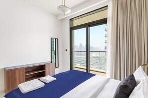 Ein Hotelzimmer mit einem großen Bett, einem Fernseher und Blick auf die Stadt durch ein großes Fenster.