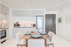 A modern kitchen with white cabinets, a built-in microwave, and a stainless steel refrigerator. - Silkhaus Elegant 1bdr Sea View Private Beach (Dubai)