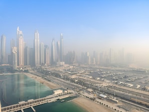 An aerial view of a modern cityscape with high-rise buildings, a marina, and a large body of water. - Silkhaus 1bdr w Sofa Bed Private Beach Access (Dubai)