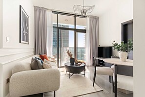 A modern living room with a sofa, a round coffee table, a dining area with a table and chairs, and a large window with curtains. - Silkhaus Modern 2BR Merano Tower in Business Bay (Dubai)