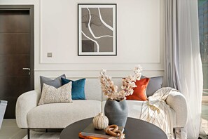A modern living room with a sofa, a coffee table, and a framed artwork on the wall. - Silkhaus Modern 2BR Merano Tower in Business Bay (Dubai)