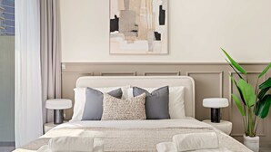 Ein ordentlich bezogenes Bett mit weißer Decke, zwei Kissen und einer gewobenen Tagesdecke. Zwei Nachttische mit Lampen, ein Blumentopf und ein Wandbild sind über dem Bett angebracht.