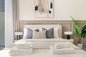 A neatly made bed with a white comforter, two pillows, and a woven throw. There are two bedside tables with lamps, a potted plant, and a wall art piece above the bed. - Silkhaus Modern 2BR Merano Tower in Business Bay (Dubai)