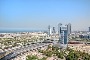 A high-rise building with a modern design, surrounded by a cityscape with multiple high-rise buildings and a highway. - Silkhaus Large Studio Madison Res High Floor (Dubai)