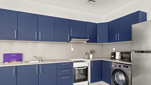 Eine moderne Küche mit blauen Schränken, einem Edelstahlkühlschrank, einem Einbauofen und einer Waschmaschine.