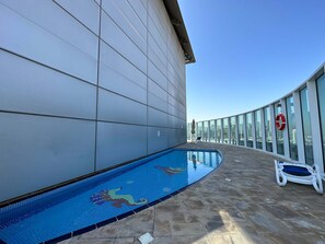 A swimming pool with a mosaic design, a lifebuoy, and a lounge chair on a rooftop terrace. - Silkhaus Large Studio Madison Res High Floor (Dubai)