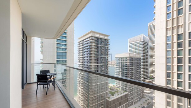 A modern apartment with a balcony, large windows, and a view of surrounding high-rise buildings. - Silkhaus Chic Seaview 1bdr Marina Vista Tower (Dubai)