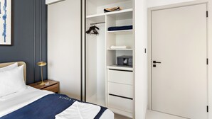 Un dormitorio con cama, mesita de noche y un vestidor con estantes y espacio para colgar.