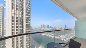 Ein Balkon mit Glasgeländer mit Blick auf einen Yachthafen und die Stadtlandschaft.