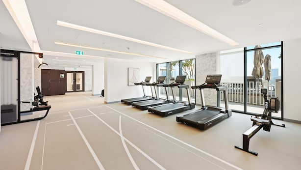 Une salle de sport équipée de tapis de course, d’un rameur et d’un vélo d’appartement.