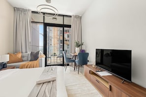 A modern hotel room with a large bed, a desk with a chair, a TV, and a balcony with a view of the city. - Silkhaus Holiday Studio Stay in Al Maryah Vista (Abu Dhabi)
