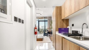 Ett modernt hotellrum med ett litet kök, en matplats och utsikt över staden.